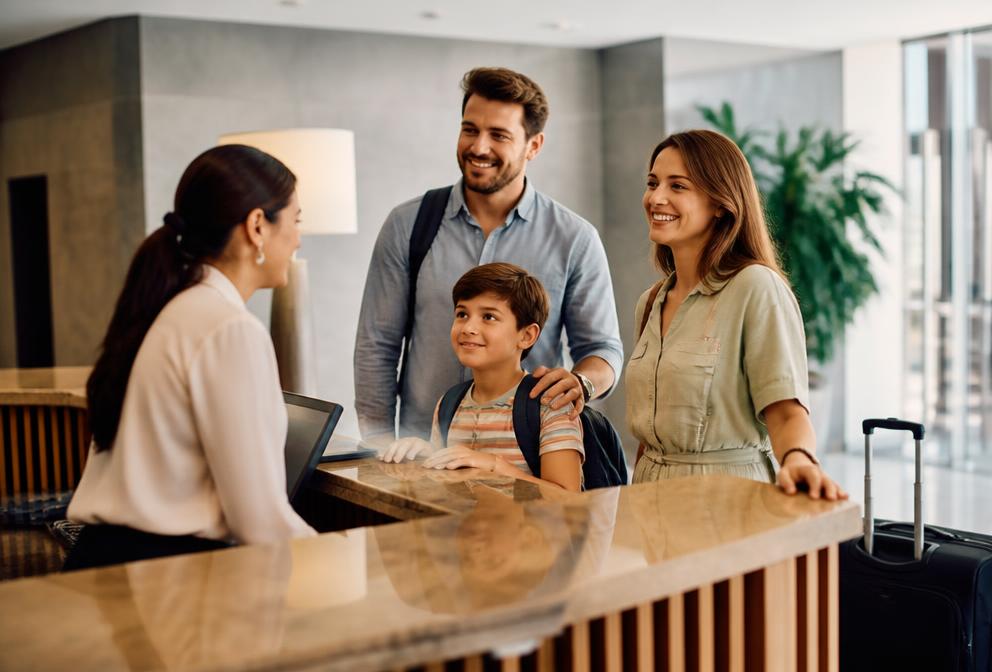 Hotel front desk employee welcoming a traveling family
